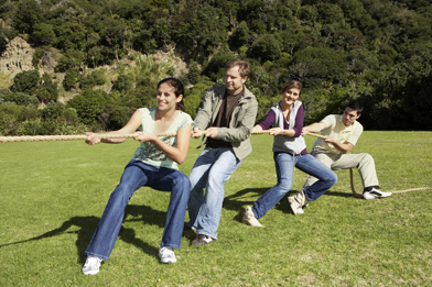 This is a photo of friends playing tug-of-war in a park.