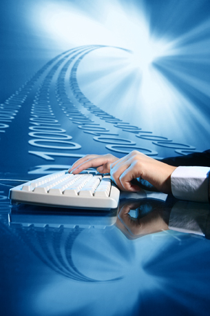 This photograph shows hands on keyboard as a wave of binary numbers comes from it.