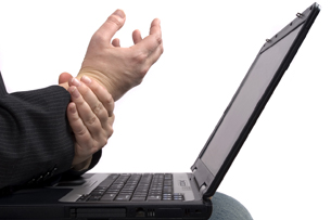 Man rubbing his hand working at his laptop.
