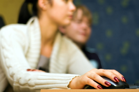 This photograph shows a boy and a girl at a computer.