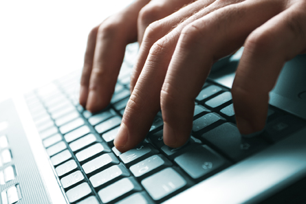 This photograph shows male hands on a laptop.