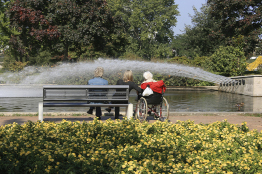 This is a photo of three women sitting in front of a pond in a park.