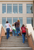 This shows a photo of students walking up the steps to the front entrance of a school.