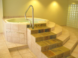 This photo shows an indoor hot tub surrounded by square ceramic tiles.