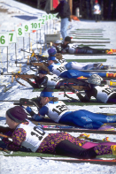 This shows a photo of biathlon athletes aiming their guns at distant targets.