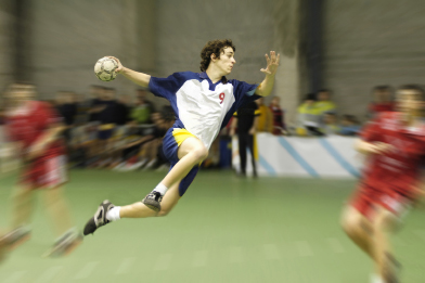 This shows a photo of a handball player jumping with the ball.