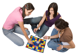 This shows a photo of three girls playing a board game.
