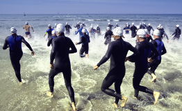 This shows a photo of triathlon competitors entering the water for the swimming portion of a race.