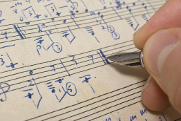 This shows an image of a person writing musical notes on a page.