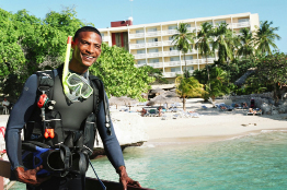 This shows a photo of a scuba diver at an ocean-side resort.