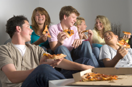 This shows a photo of a group of young people eating pizza.