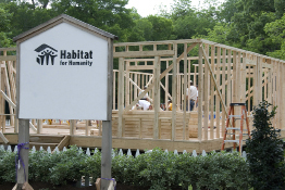 This shows a photo of the volunteer group Habitat for Humanity working on new home construction.