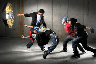 This shows a photo of four young men performing a hip hop dance routine.