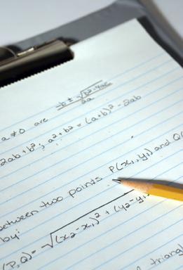 This photo shows radical expressions written on paper on a clipboard. There is also a pencil in the photo.