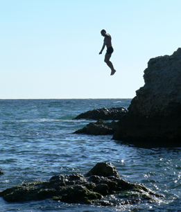 This photo shows a man that jumped off a cliff is about to land in the water.