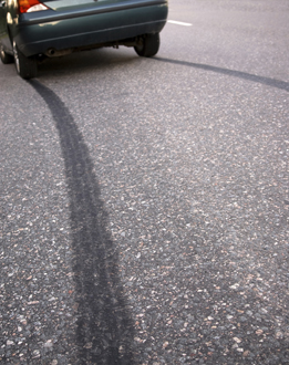 This photo shows a car and skid marks on the road made by the car.