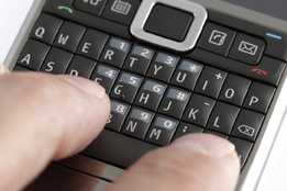 This is a photo of fingers texting on a cellphone keyboard.