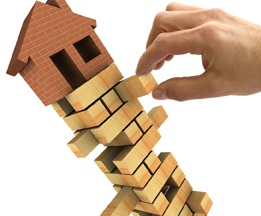 This is a photo of a house balanced on top of a stacked puzzle.
