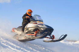 This photograph shows a snowmobile racing across an open field.