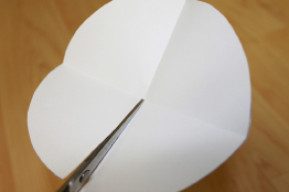 This photo shows a paper circle folded into quarters. The circle is being cut along one radius.