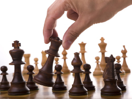 This photo shows two chess boards and pieces. One board is table top size. The other chess board is much larger, taking up space on a patio.