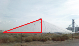 This photo is of a tarp-covered, conical grain pile 316 ft in diameter. A right triangle is overlaid on this grain pile. The hypotenuse of this triangle follows the slanted side. The horizontal side of the triangle follows the bottom of the grain pile, and the vertical side of this triangle follows the centre of the pile.