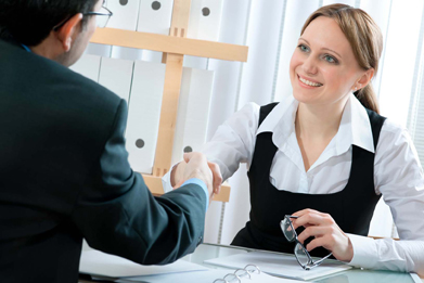 This photo shows a young woman smiling and shaking the hand of her future employer at the end of a job interview.