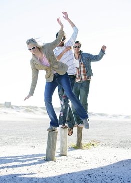 This is a photo of three people balancing on log posts.