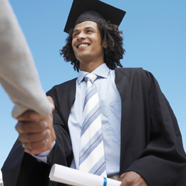 This is a photo of a man dressed in a graduation gown and mortarboard. He is receiving his diploma.