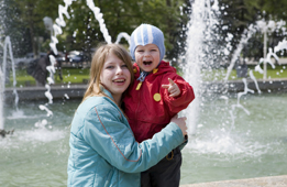 This is a photo of two young people in front of a fountain that sprays water. 