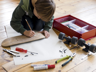 This is a photo of a young boy customizing a skateboard.