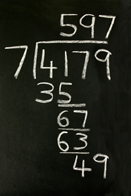 This shows a long division problem written on a blackboard. The problem shows that 4179 divided by 7 is 597.
