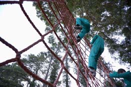 This photo shows members of a team climbing a net wall as part of an obstacle race.