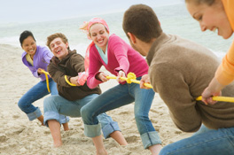 This is a photo of a group of friends in a tug-of-war match on a beach.