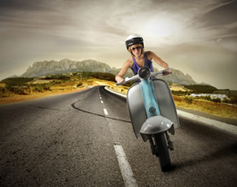This is an image of a woman riding a scooter on a stretch of highway.