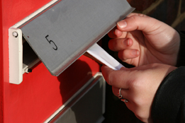 This is a photo of a woman inserting a flyer through a mail slot.