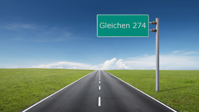 This shows an illustration of a stretch of highway with green grass on either side. A signpost indicates that the distance to Gleichen is 274 km.