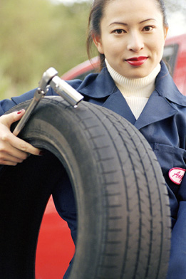 This is a photo of a female mechanic holding a tire.