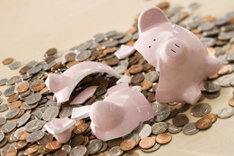 In this photo a broken piggybank is shown with coins scattered around the bank.