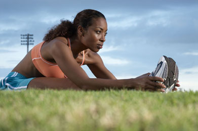 In this photo an athlete is stretching her leg muscles.