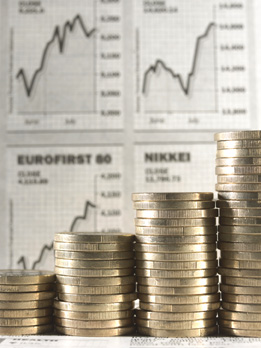 Coins are stacked up in front of financial graphs.