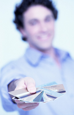 This photo is a close-up of a collection of credit cards in a man’s hand.