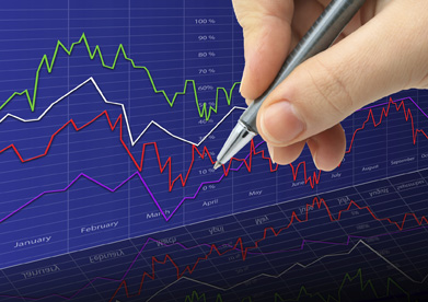 A pen in someone’s hand checks off financial graphs in this photograph.