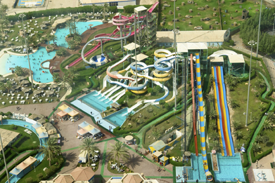 This is an image showing an extensive water park. There is a wave pool and many different shapes of slides.