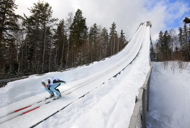 This photo shows a ski jumper who is almost ready to lift off.