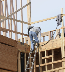 This is a photo of a man standing on a ladder at a construction site.