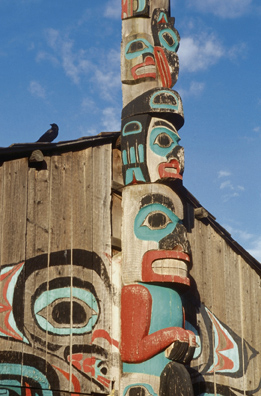 This is a photo of a totem pole and a First Nation home.