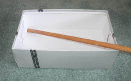 This photo is of a stick diagonally propped in an open box.