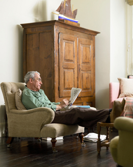 This is a photo of a man sitting beside a cabinet.