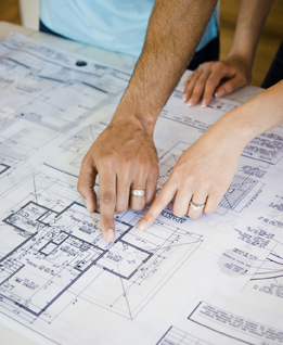 This is a photo of two people looking over house blueprints.